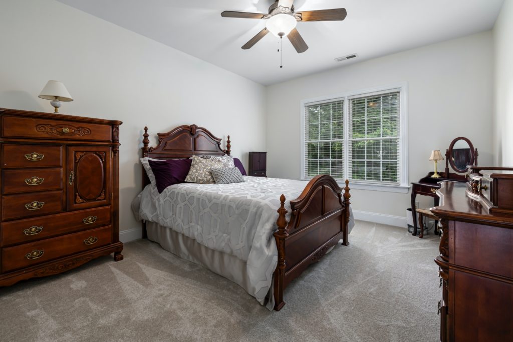 bedroom furniture, brown dresser, table and bed in a bedroom