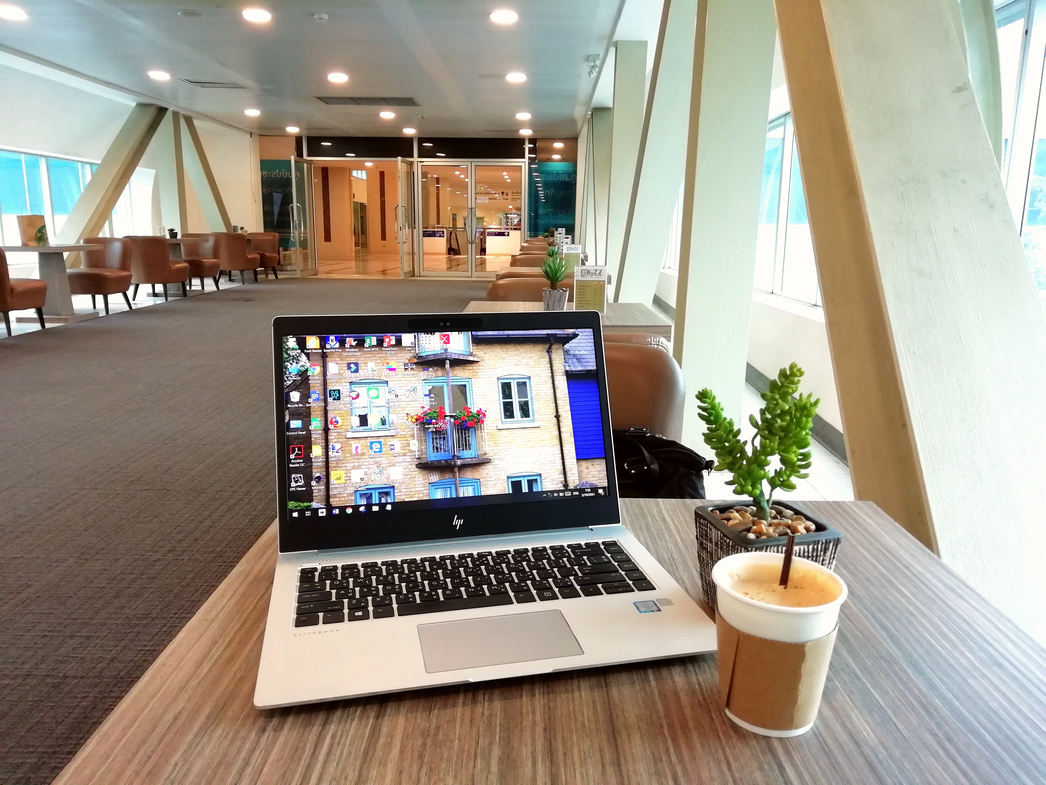 a laptop on a brown table with a cup of coffee