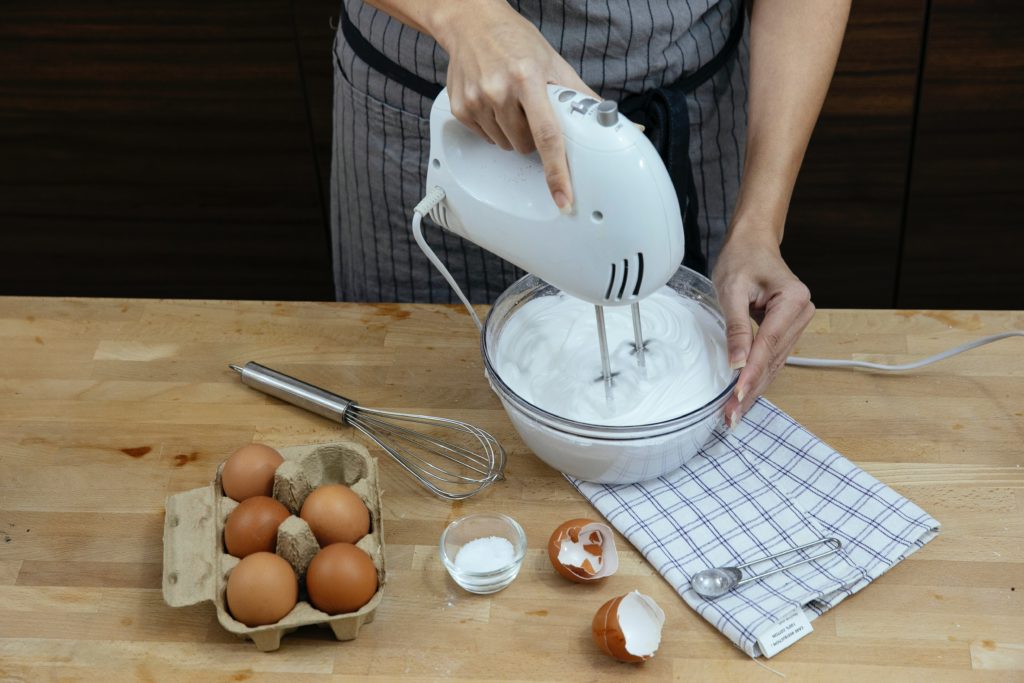 a woman is mixing eggs and flour with a mixer