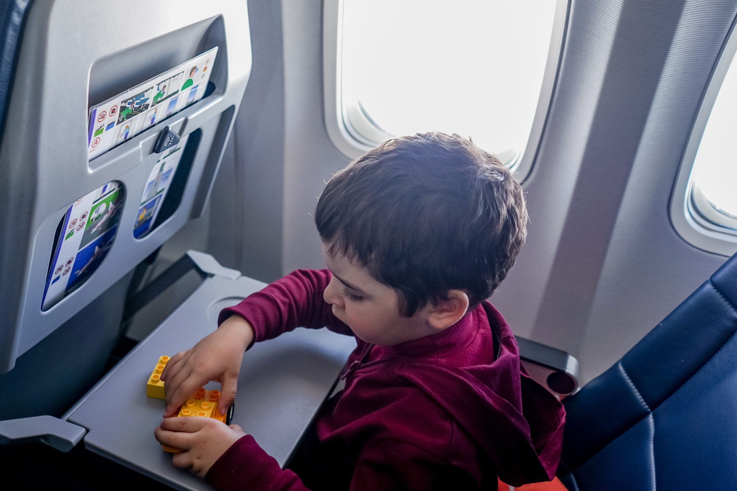 flying with kids, a boy is sitting in an airplane on his seat