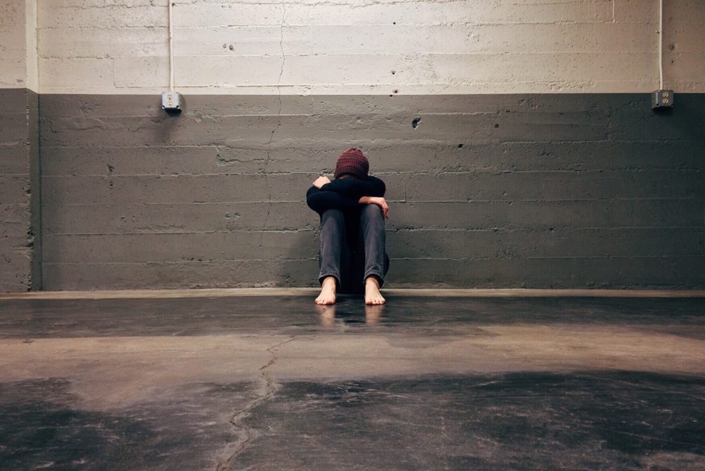 depression, a man is sitting alone by a wall and covering his face