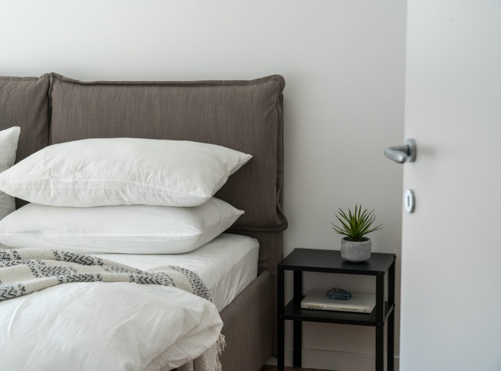 a pillow, two white pillow on a gray bed with black table