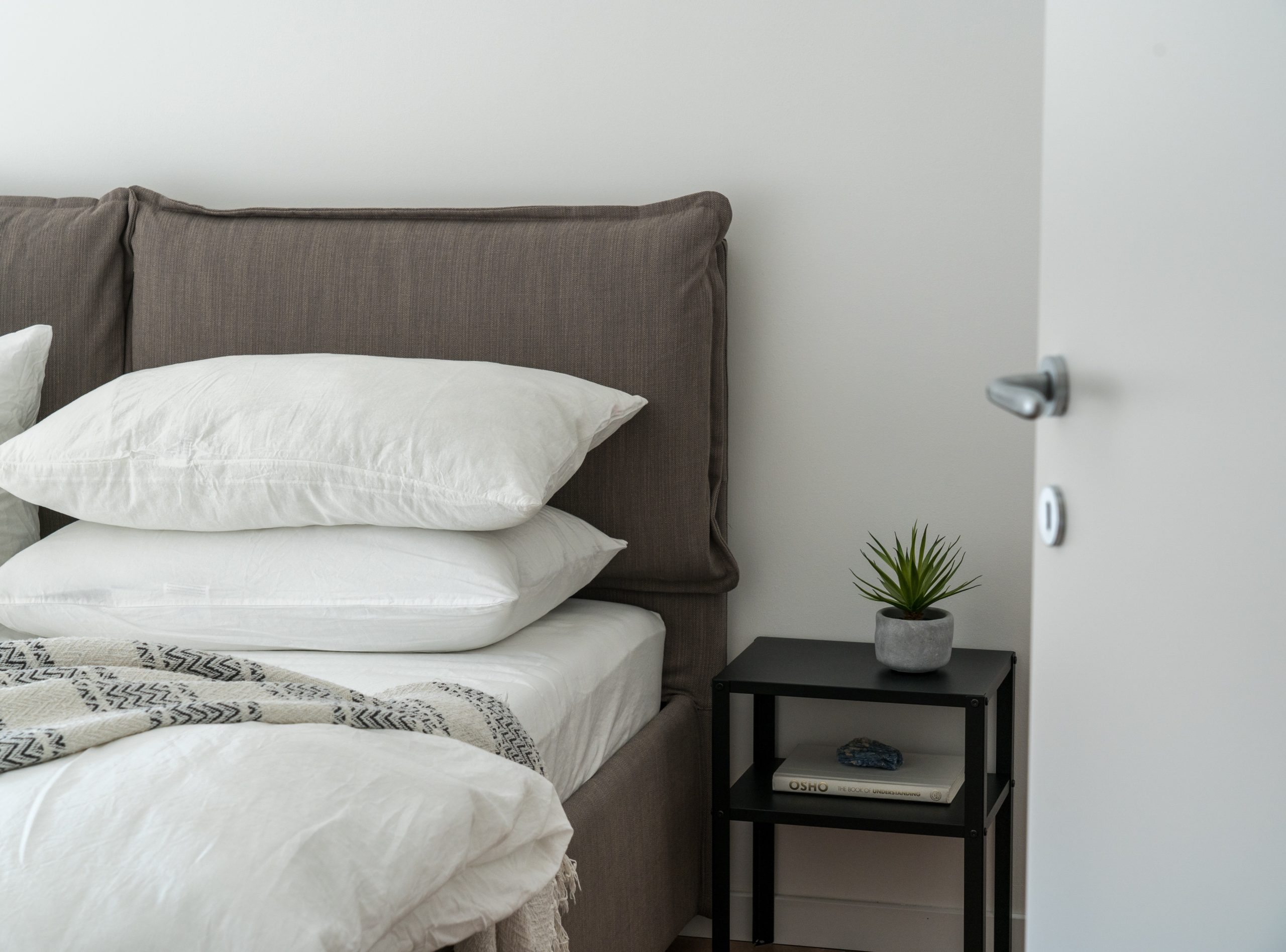 a pillow, two white pillow on a gray bed with black table