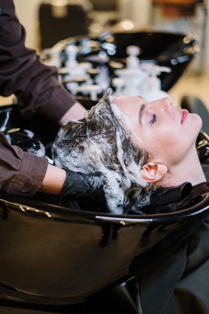 a shampoo, a barber is washing a woman hair with shampoo at a barbershop