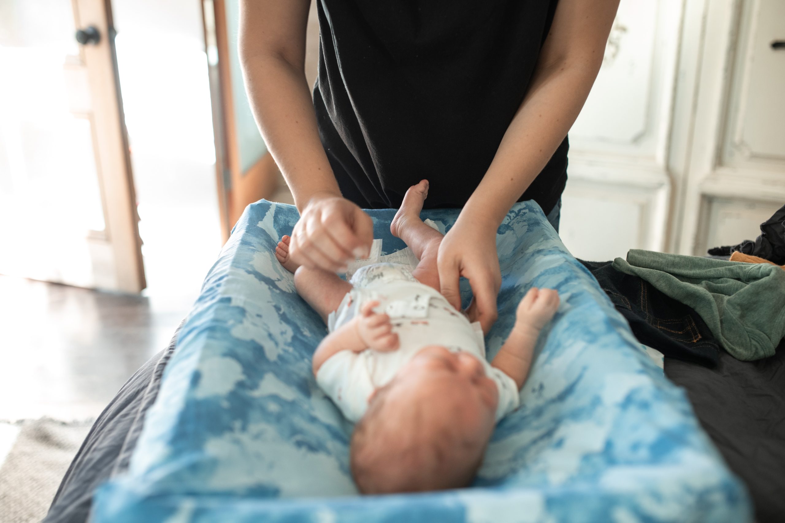 a father positioning his baby on a blue mattress