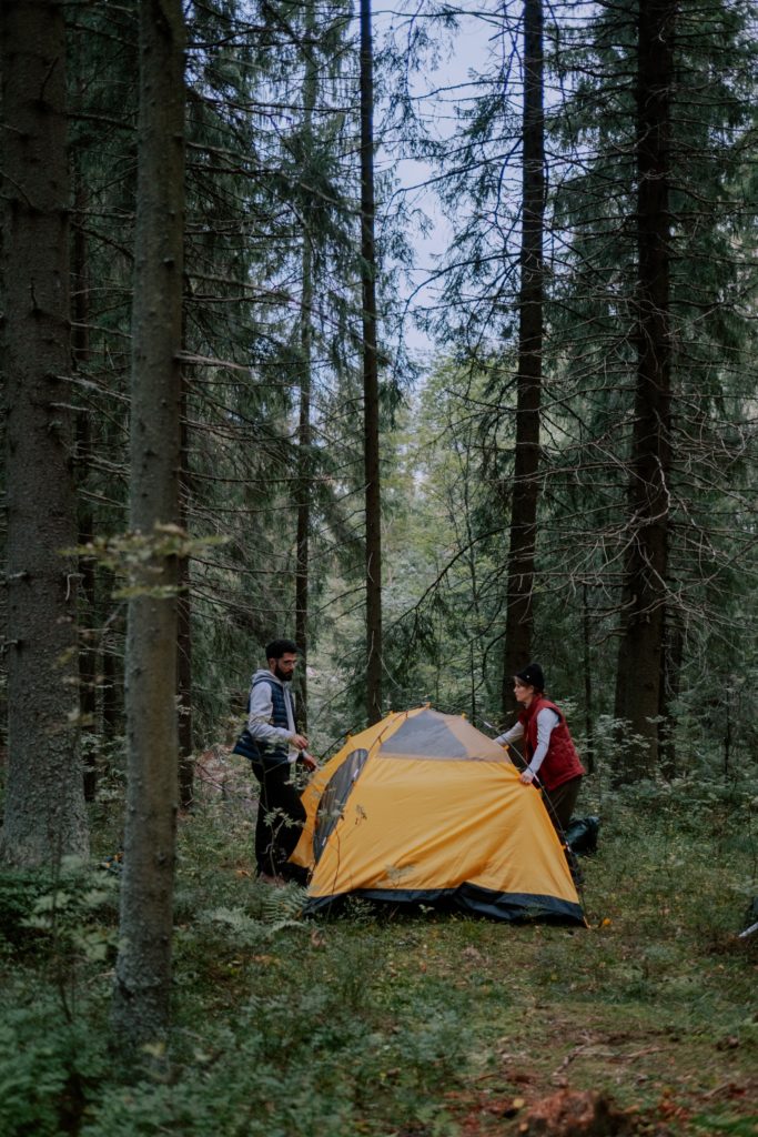 a man and a woman building a yellow tent in the forest, how to shop for a travel tent